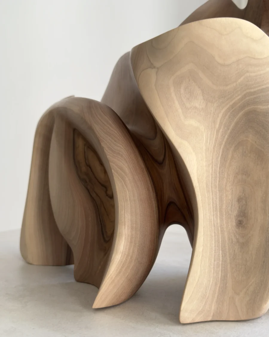 Close-up detail of Unfurl showing the natural walnut grain, smooth hand-finished surface and carved transitions between flowing forms.