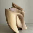 Side profile of Unfurl in direct sunlight, showing the sculpture’s narrow layered silhouette and strong interplay of light and shadow.