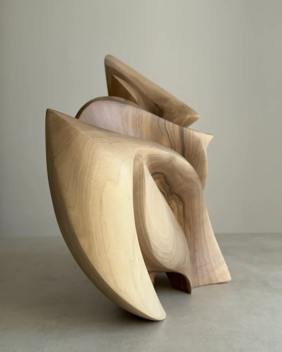 Side profile of Unfurl in direct sunlight, showing the sculpture’s narrow layered silhouette and strong interplay of light and shadow.