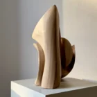 Sunlit side profile of Unfurl walnut sculpture, with warm light tracing the tall carved edge and layered organic silhouette.