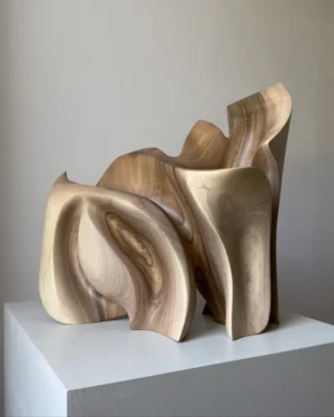 Front view of Unfurl walnut sculpture in natural light, revealing the rhythm of its upright carved planes and smooth walnut surfaces.