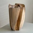 Angled view of Within highlighting its layered construction, curved walnut planes and changing light across the carved edges.