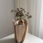 Angled view of Within with a dried botanical stem rising from the central opening between sculpted walnut planes.