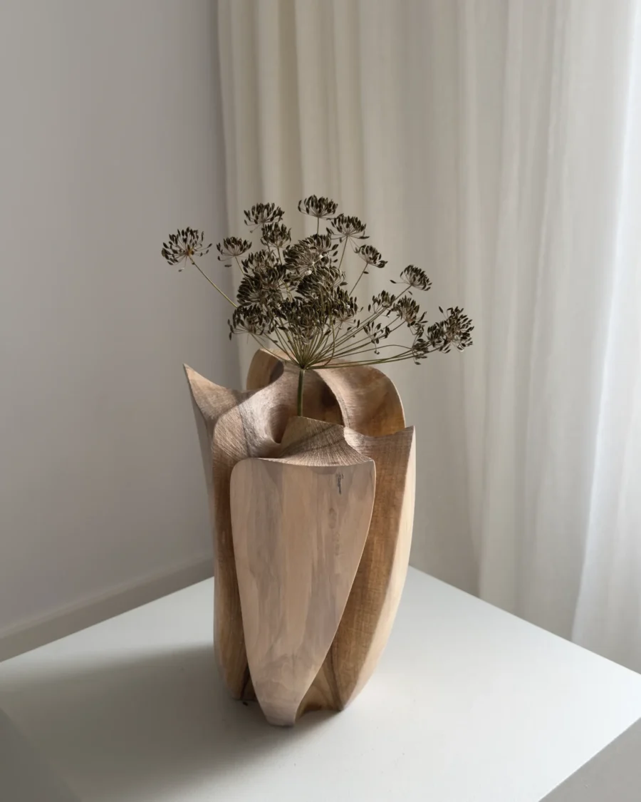 Angled view of Within with a dried botanical stem rising from the central opening between sculpted walnut planes.