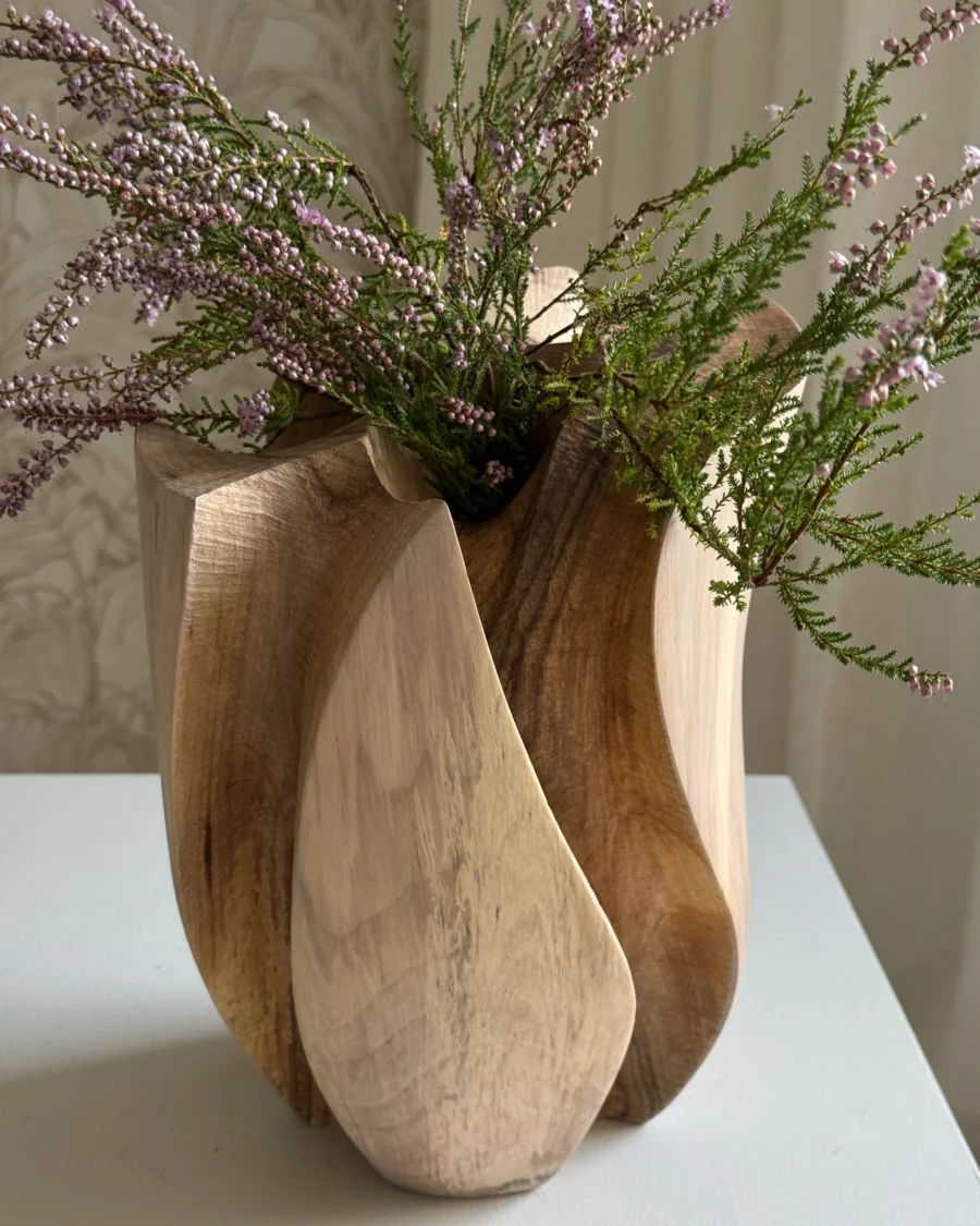 Close view of purple heather inside Within, surrounded by sweeping carved walnut surfaces and darker recessed areas.