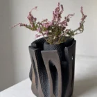 Construct applewood vessel with heather arrangement, photographed in natural light from a slightly elevated angle.