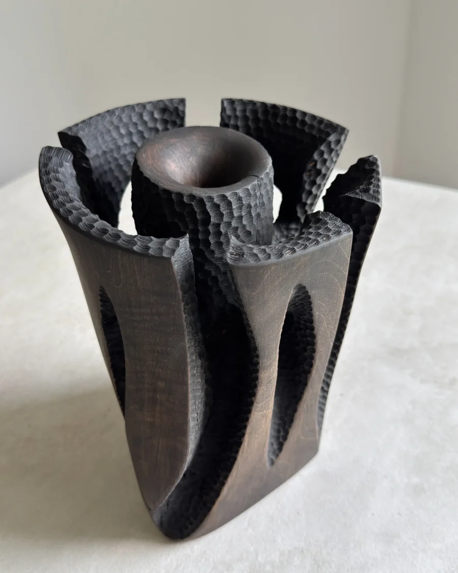 Top detail of Construct, a dark hand-carved applewood sculptural vase with textured openings around a central core.
