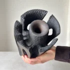 Hand-held top view of Construct showing the central opening, carved inner texture and segmented sculptural form.
