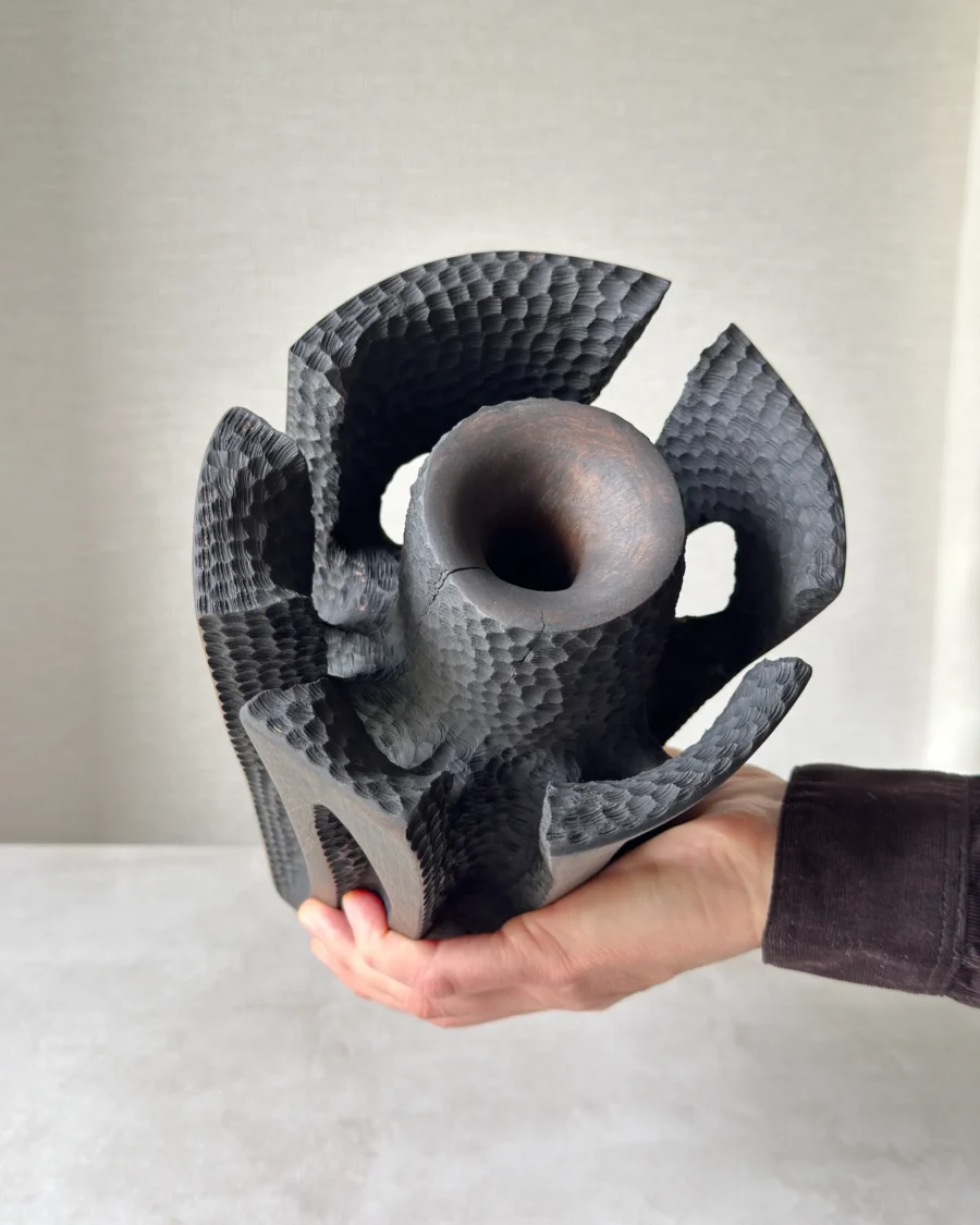 Hand-held top view of Construct showing the central opening, carved inner texture and segmented sculptural form.