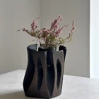 Dark hand-carved applewood vase with heather branches, showing the contrast between smooth outer planes and textured recesses.