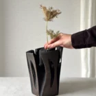Hand placing dry stems into the central opening of Construct, showing the vase scale and practical use.