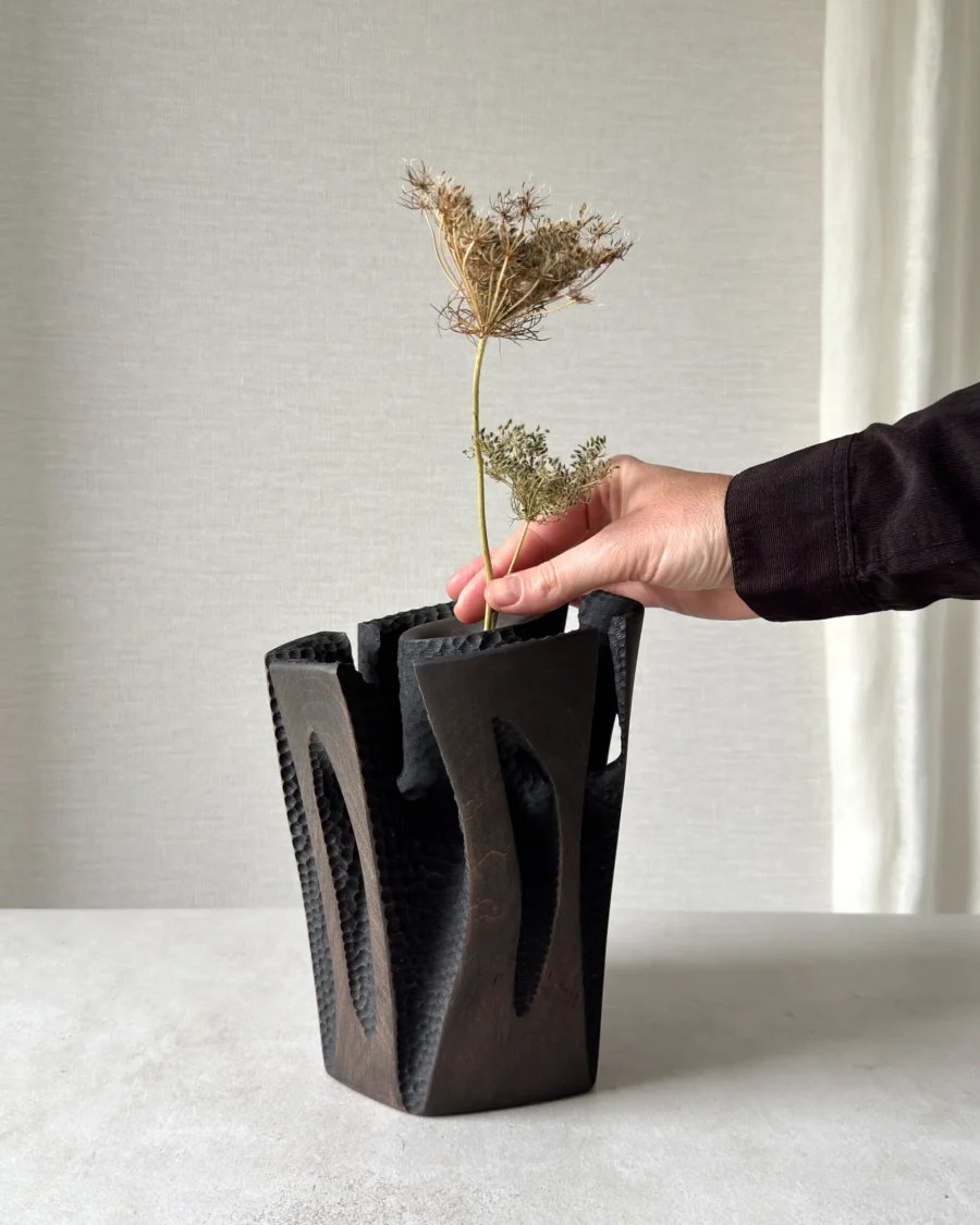 Hand placing dry stems into the central opening of Construct, showing the vase scale and practical use.