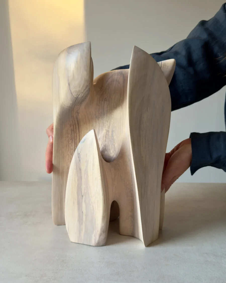 Hand-carved walnut sculpture Embrace shown with the artist’s hands to demonstrate its scale and sculptural presence