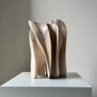 Side view of Embrace, a hand-carved European walnut sculpture with overlapping organic forms and natural grain