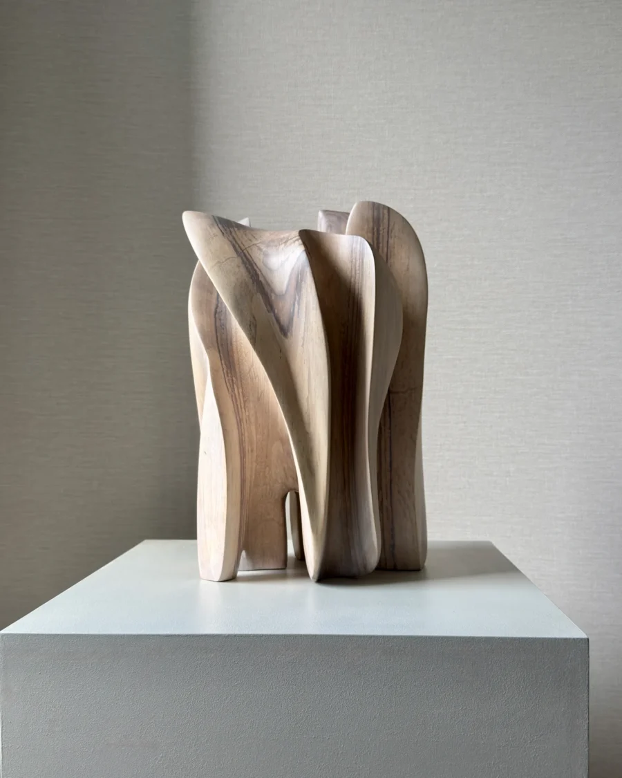 Side view of Embrace, a hand-carved European walnut sculpture with overlapping organic forms and natural grain