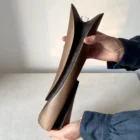 Emergence sculptural wooden vase held in two hands to show its 34 cm height, curved planes and dark recessed carving.