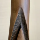 Close-up of Emergence hand-carved cherry wood vase showing the contrast between smooth brown wood and a dark textured recessed surface.