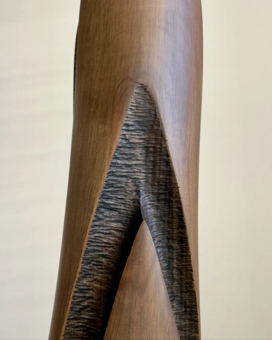 Close-up of Emergence hand-carved cherry wood vase showing the contrast between smooth brown wood and a dark textured recessed surface.
