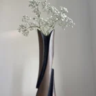 Sculptural cherry wood vase with white gypsophila arranged in the glass insert, showing the contrast between warm brown wood and dark texture.