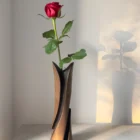 Hand-carved cherry wood bud vase with a fresh red rose in the removable glass tube, photographed in warm natural light.