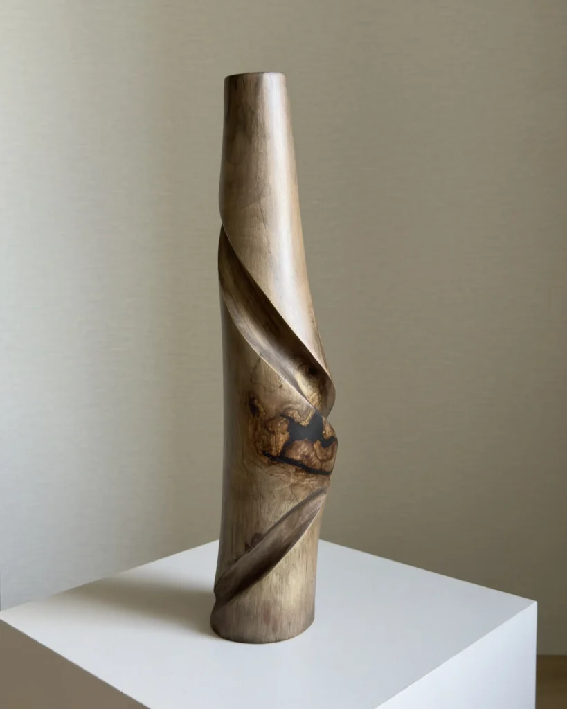 Front view of Quiet Turn, a hand carved walnut wood vase with black resin inclusion and sculptural diagonal movement.