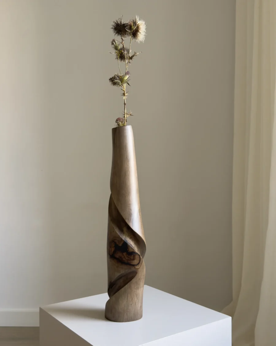 quiet-turn-sculptural-vase-dried-thistle Tall walnut wood vase Quiet Turn with a single dried thistle stem, showing its narrow sculptural proportion and soft natural light.