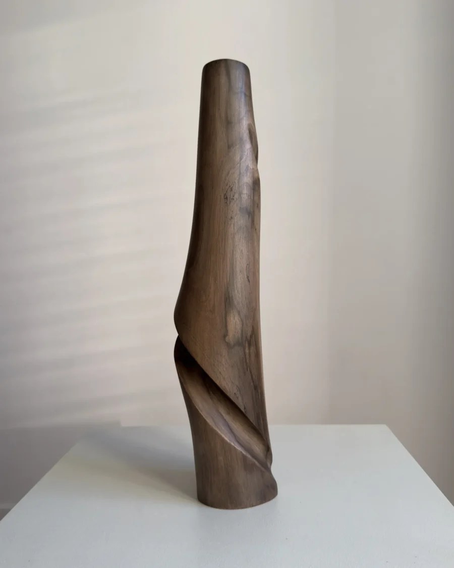 quiet-turn-sculptural-walnut-vase-side-view Side view of Quiet Turn, a hand carved walnut vase with a smooth tapered body and deep flowing carved recess.