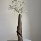 quiet-turn-walnut-vase-babys-breath Quiet Turn walnut sculptural vase with delicate white baby’s breath, emphasizing its tall organic modern silhouette.